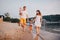 Family vacation in summer. Young Caucasian family foot walking barefoot sandy beach, shore river water. Dad mom holding hands two