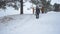 Family vacation in winter with a dog in park, a man clears a pile of snow, winter forest.