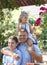 Family on a walk in the summer. Father, son and daughter are having fun in nature. Little daughter sitting on dad`s shoulders.