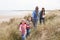 Family Walking Along Dunes On Winter Beach