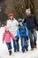 Family Walking Along Snowy Street In Ski Resort