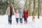 Family Walking Dog Through Snowy Woodland