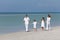 Family Walking & Holding Hands On Beach