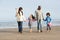 Family Walking By Sea On Winter Beach