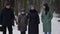 Family is walking at winter, little girl with mother and grandparents is strolling in snowy park or forest