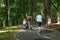 Family walks in park. Mother with stroller and two sons. Back view