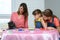 The family watches as the cat plays a chip from the table from the board game