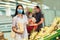 Family wearing face protective medical masks for protection from virus disease with shopping cart buying food at supermarket