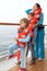 Family wearing in life jackets stand at deck