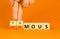 Famous or anonymous symbol. Concept word Famous and Anonymous on wooden cubes. Businessman hand. Beautiful orange table orange