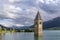 The famous bell tower of old Curon, submerged in Lake Resia, South Tyrol, Italy, with the snow capped Alps in the background