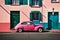 Famous bright color retro car parked by colorful houses in Bo Kaap district in Cape Town.