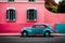 Famous bright color retro car parked by colorful houses in Bo Kaap district in Cape Town.