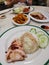 Famous chicken rice the staple food of Malaysia with mixed vegetable and crispy sliced fried pork.