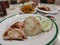 Famous chicken rice the staple food of Malaysia with mixed vegetable and crispy sliced fried pork.