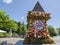 The famous clock tower, one of the city of Graz attractions, made of flowers and the real Clock Tower Grazer Uhrturm in the