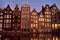 Famous dancing houses of the Damrak canal in Amsterdam on dusk