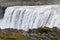 The famous Icelandic giant Dettifoss waterfall and a woman dressed in yellow in the foreground.