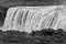 The famous Icelandic giant Dettifoss waterfall and a woman dressed in yellow in the foreground.