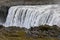 The famous Icelandic giant Dettifoss waterfall and a woman dressed in yellow in the foreground.