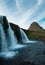 Famous icelandic waterfalls with looming Kirkjufell arrowhead mountain in background