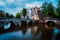 Famous Keizersgracht Emperor`s canal in Amsterdam, dutch scenery with illuminated bridge at twilight, Netherlands