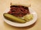 Famous Pastrami on rye sandwich served with pickles in New York Deli