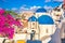 Famous Santorini view. Three blue domes and traditional white houses with bougainvillea flowers. Oia village, Santorini island,