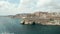 Famous Siege Bell War Memorial in Valletta, Malta capital City, Aerial Drone backwards, Revealing a passing Cargo Ship