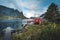 Famous tourist attraction of Reine in Lofoten, Norway with red rorbu houses, clouds, rainy day with bridge and grass and