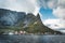 Famous tourist attraction of Reine in Lofoten with view towards Reinebringen, Norway with red rorbu houses, clouds