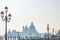 Famous venezian street lamps with pink glass in front of Basilica Santa Maria della Salute in Venice in the fog