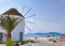 Famous white windmill in typical Greek island landscape on summer day. Cruise liner navigate harbor. Sea voyage