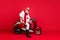 Fancy grandfather santa man posing sitting on vintage moped wear jumper and trousers isolated red background