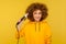 Fancy positive woman holding curling iron, making perfect afro hairdo, trendy girl ironing hair curls