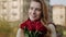 Fancy woman with flowers outdoors. Hipster girl enjoying bouquet on street.