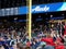 Fans in bleachers do the wave with scoreboard above featuring Alaska Airlines ad