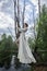 Fantastic fairy beautiful woman in white long dress on old dry tree. Girl princess in swamp. Fashion model sexy girl posing on a