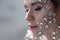 Fantastic fashion portrait of a young beautiful woman with transparent crystals on her face and shoulders.