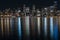 Fantastic nighttime panoramic city view with illuminated skyscrapers reflected on calm water.