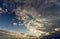 Fantastic panorama view of bright white gray dark wide puffy clouds lit by sun spreading against deep blue sky moving with wind.