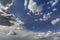 Fantastic panorama view of bright white puffy clouds lit by sun spreading against deep blue summer sky moving with wind. Beauty an