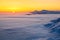 Fantastic scenery with the high mountains in snow, dense textured fog and a sunrise in the cold winter day.