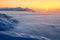 Fantastic scenery with the high mountains in snow, dense textured fog and a sunrise in the cold winter day. Mountains in fog.