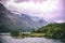 Fantastic shot of mountains, field of vegetation, and a lake under a purple sky