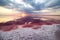 Fantastic sunset on a pink salt lake. Large crystals of salt are interestingly shaped on the shore and reflected in the red water