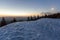 Fantastic view of evening in winter mountains. Dark green tops of pine trees behind snowy hill and first bright star in quiet blue