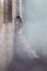 fantasy bride leaning agaisnt rustic wall surrounded by fog