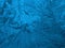 Fantasy ice crystals. Fiery blue winter wallpaper. Drawing of frost on window glass. Pattern of leaves and stems of magical