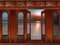 Fantasy view of an antique wooden wall panel with high windows and a French door, overlooking the sea and a setting sun.